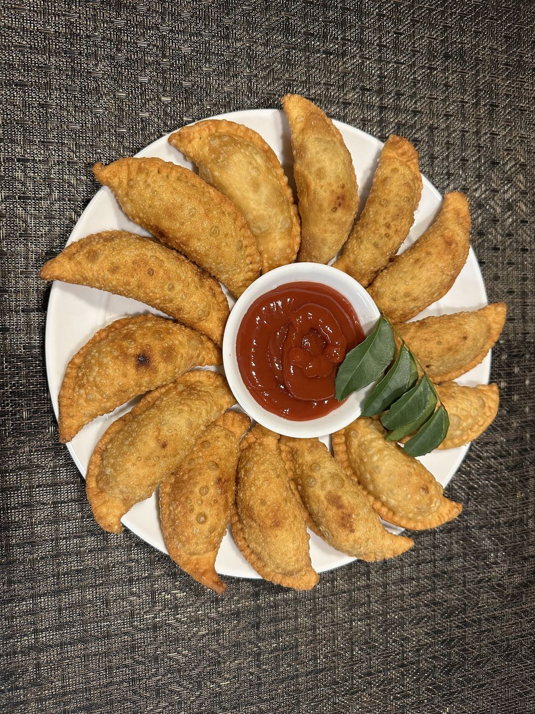 Fan of golden samosas with chilli dipping sauce